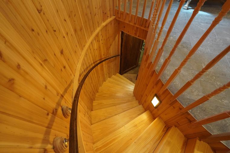 A curved cedar staircase with a laminated handrail bent to follow the wall