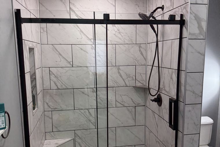 A tiled walk-in shower with black fittings and a glass enclosure