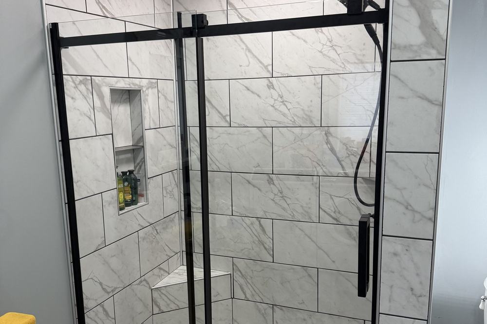 A tiled walk-in shower with black fittings and a glass enclosure