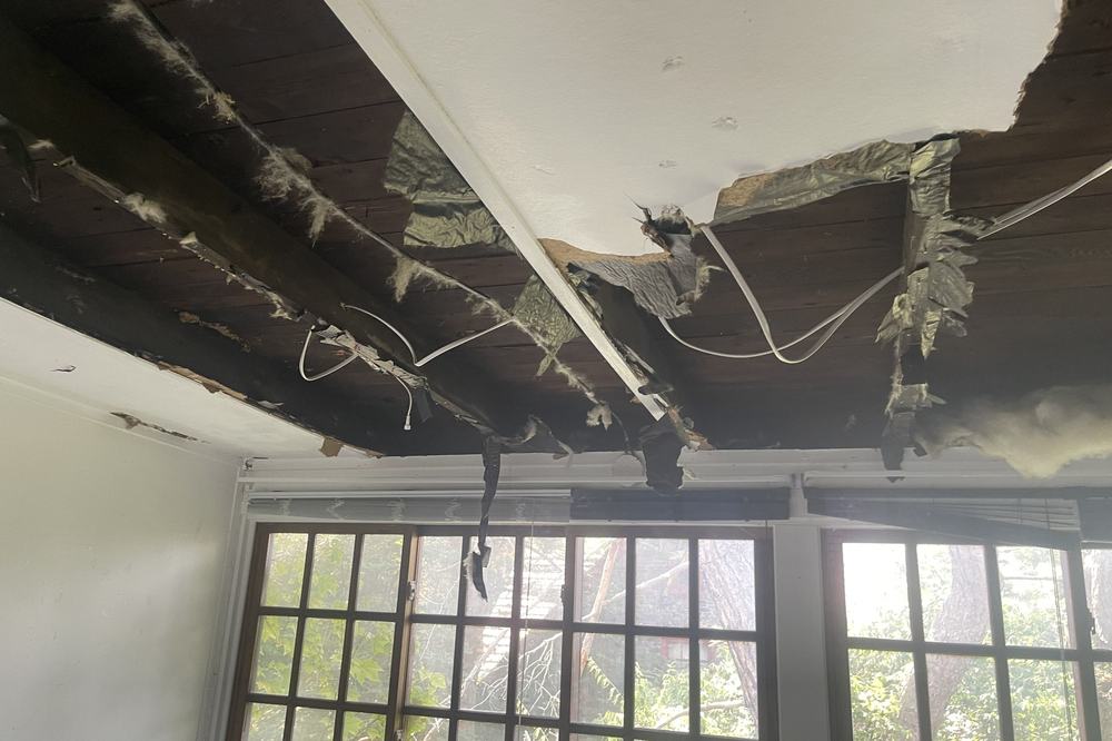 A ceiling opened up to expose failed plaster and the joists above