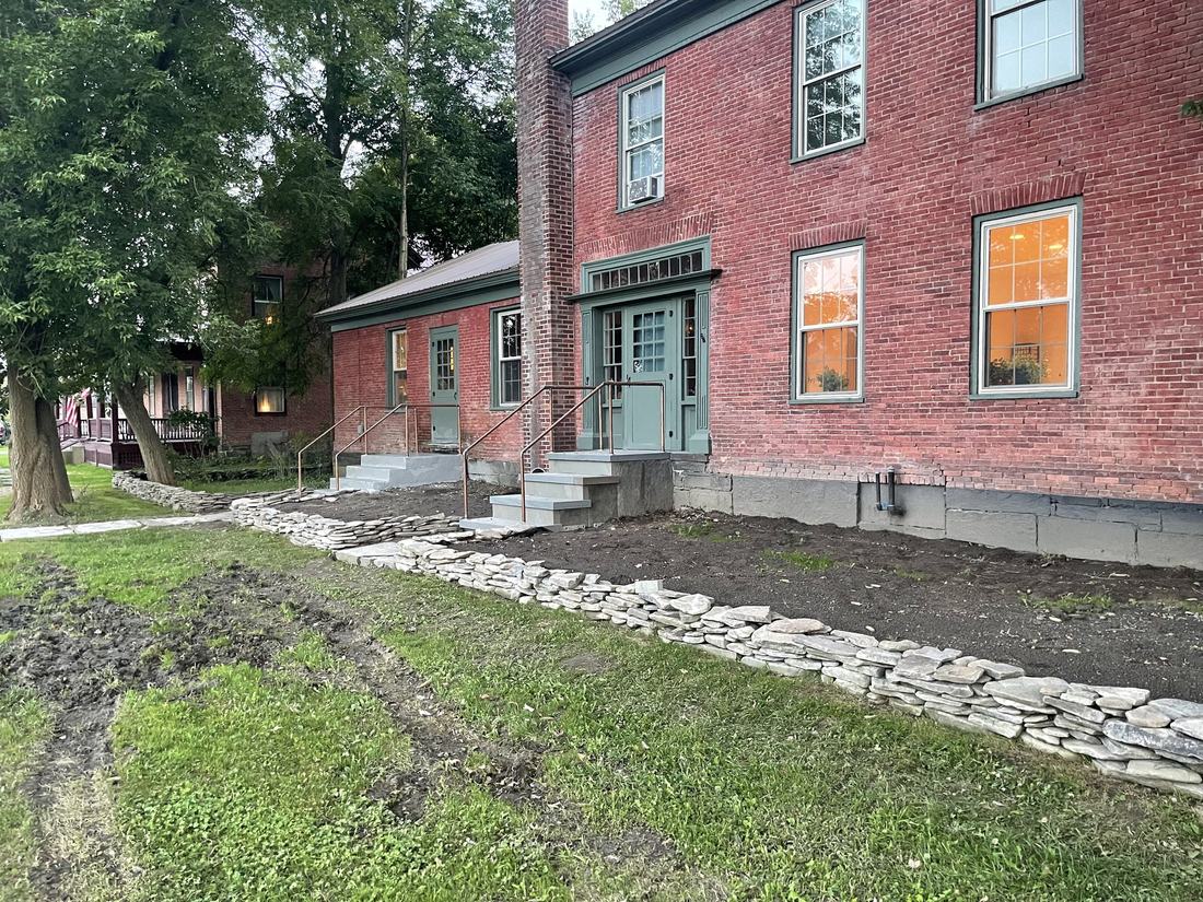 A brick house with new bluestone steps, a dry stone retaining wall and regraded ground