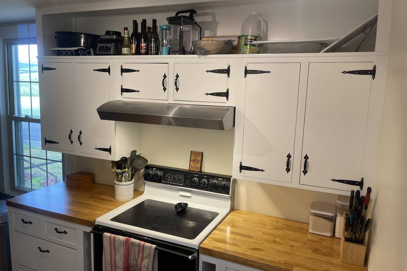 A finished kitchen with painted cabinetry and butcher block counters