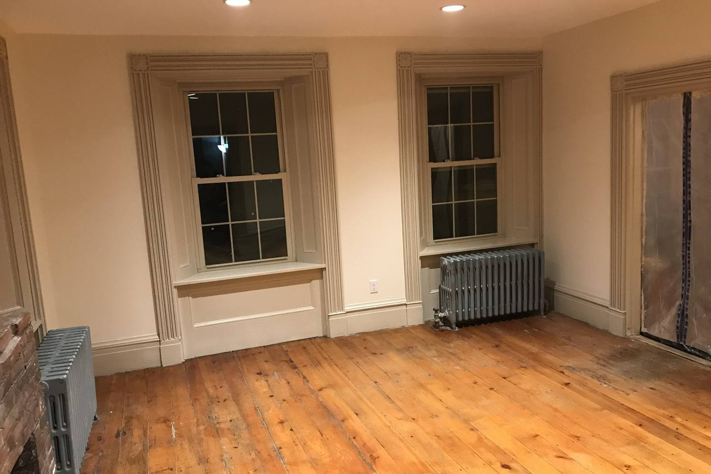 A restored room with original trim and a refinished wide-plank floor